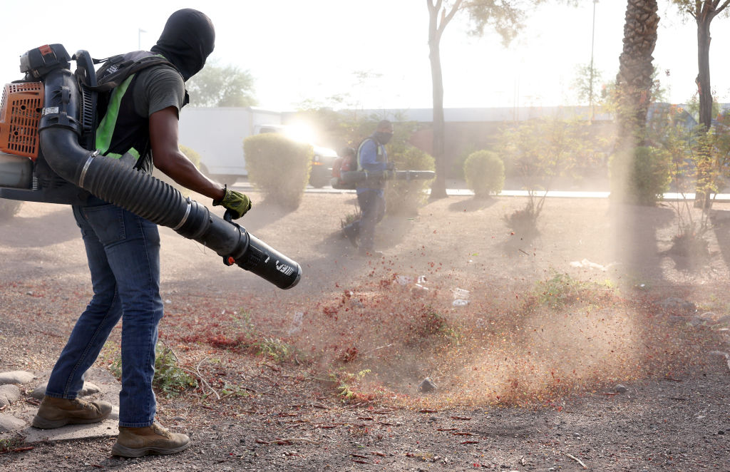 Alan Sibaja wears a head covering for sun protection while working with noisy leaf blowers